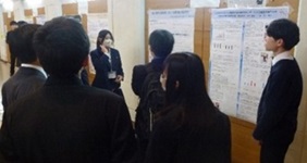 ポスター前で発表する生徒と、説明を聞く生徒たちの写真