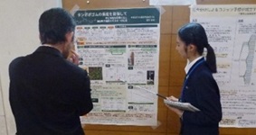 ポスター前で発表する生徒1名と、説明を聞く教員1名の写真