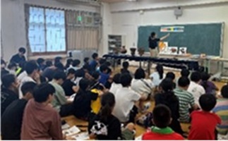 黒板の前で土器について説明する職員と、説明を聞く児童生徒の写真