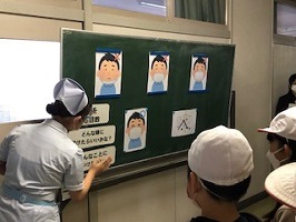 児童にマスクの付け方を教える生徒の画像