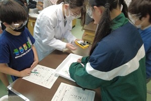 小学生と高校生が一緒に実験結果を確認している写真