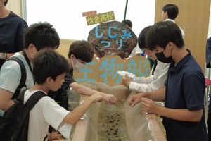 しじみ釣りブースで中学生の体験をサポートする高校生の写真