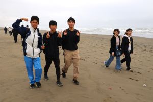 ピースをしながら海岸を歩く生徒たちの写真