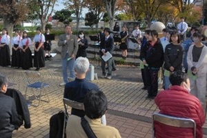 観客の前で挨拶をする白井市長と生徒たちの写真