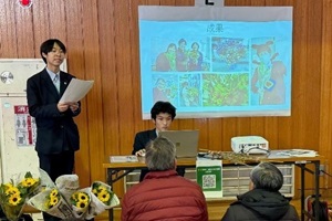 3年生2名が、育てたひまわりの切り花と共に、スクリーンの前で研究成果を発表している写真