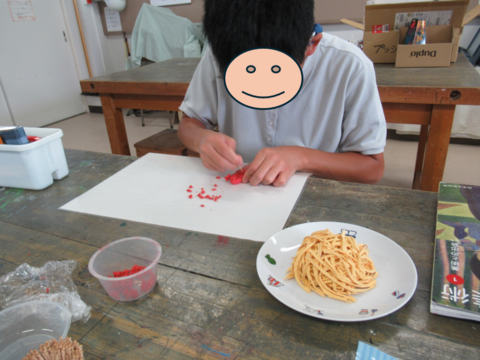 生徒が赤い紙粘土を細かくしている様子
