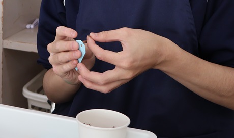 生徒が作品に使うクラフトモールを穴に通している様子