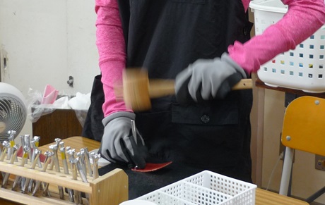 生徒が革の作品に木槌で模様を打っている様子