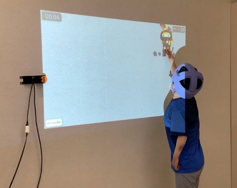 プロジェクターに投影されたキャラクターに手で触れる様子