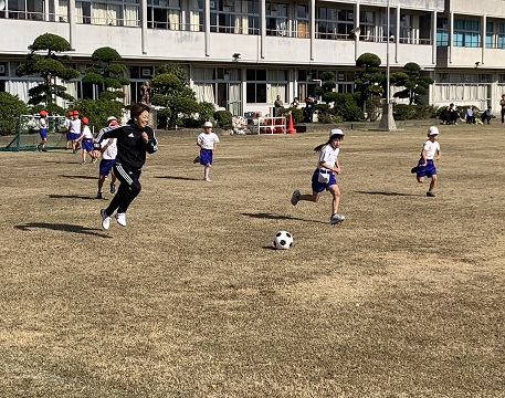宮間さんとサッカーをする児童たち。