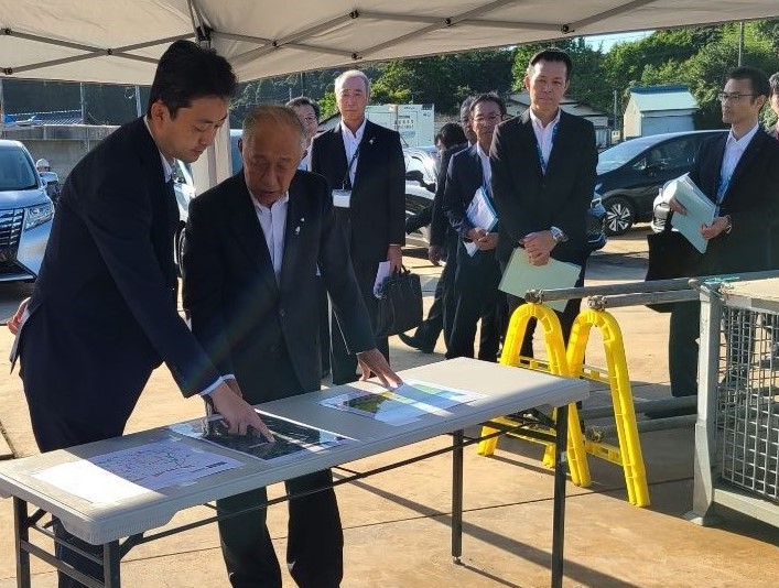 長生グリーンライン計画予定地周辺における現地視察の際、資料を見ながら村長の説明を聞く知事の画像