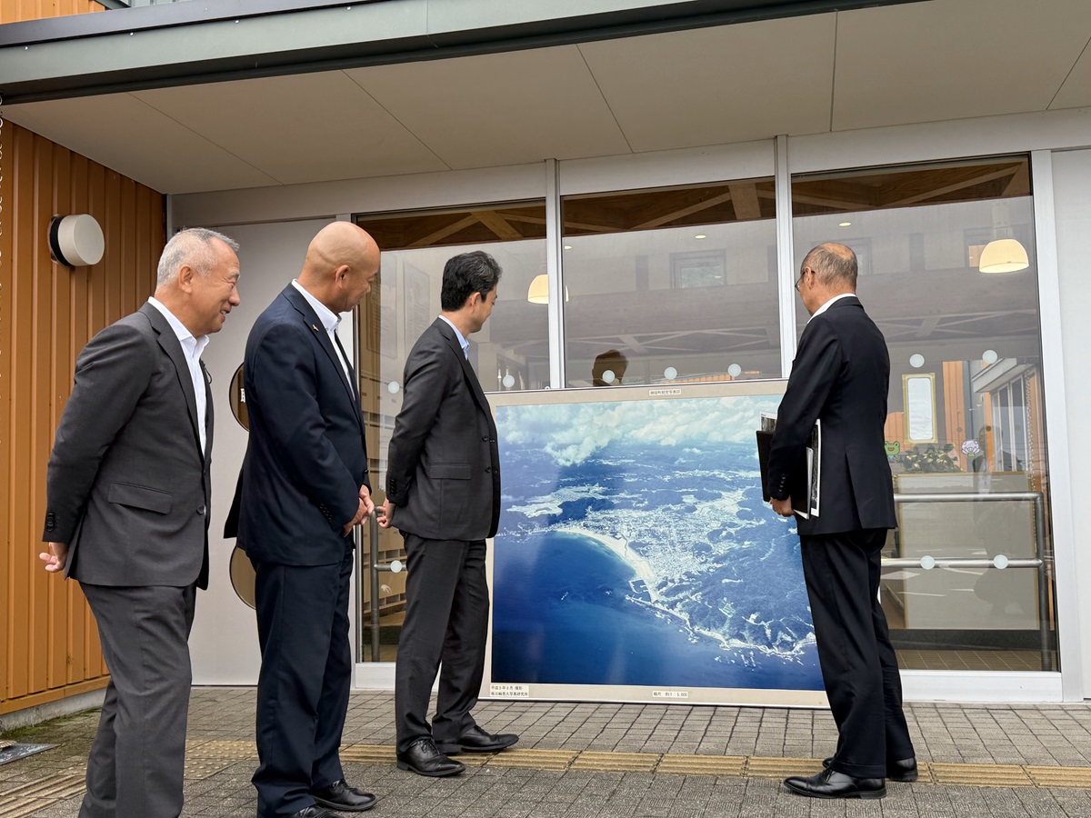 御宿駅西側周辺における現地視察の際、写真を見ながら町長の説明を聞く知事の画像