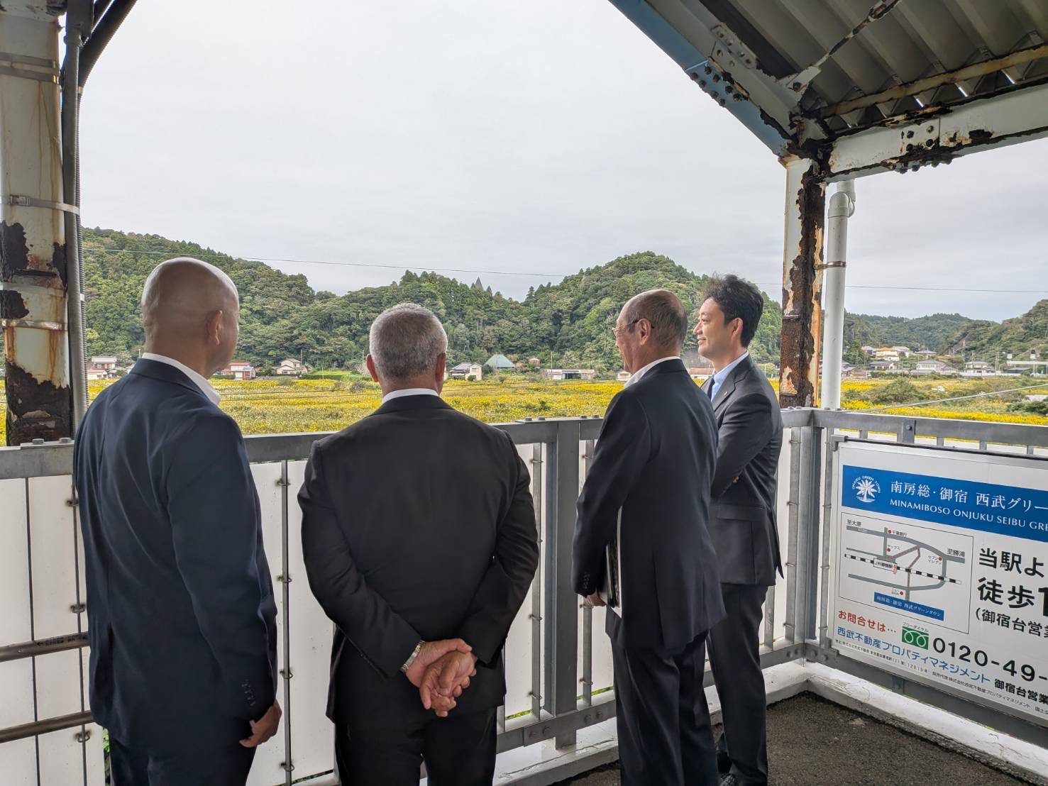 御宿駅西側周辺における現地視察の際、周辺の土地の状況を見ながら町長の説明を聞く知事の画像