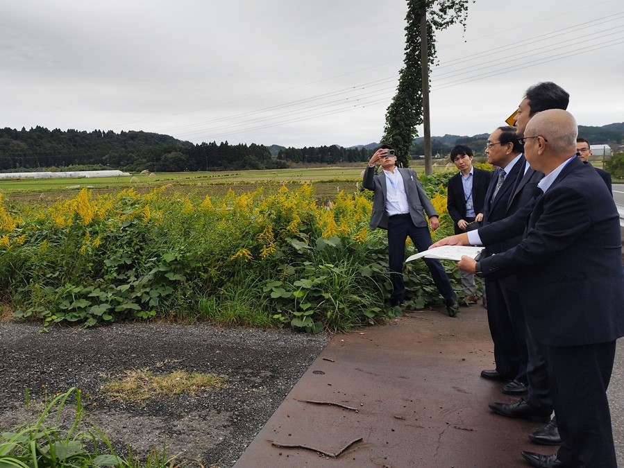 国道465号苅谷新田野バイパス整備予定地周辺における現地視察の際、周辺の様子を見ながら市長の説明を聞く知事の画像