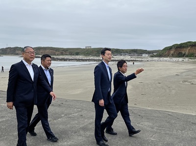 名洗港における現地視察の際、砂浜の近くを歩きながら銚子市長の説明を受ける知事の画像