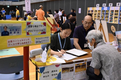 千葉ポートアリーナのちばしパラスポーツコンシェルジュ相談窓口で2名のスタッフから案内を受ける高齢の方